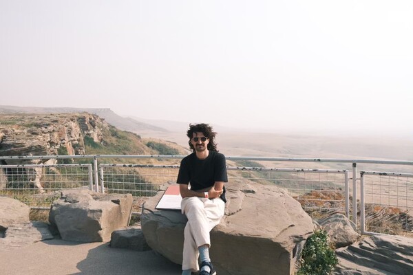Dr. Mergim Binakaj sitting in from of a rocky scenic view