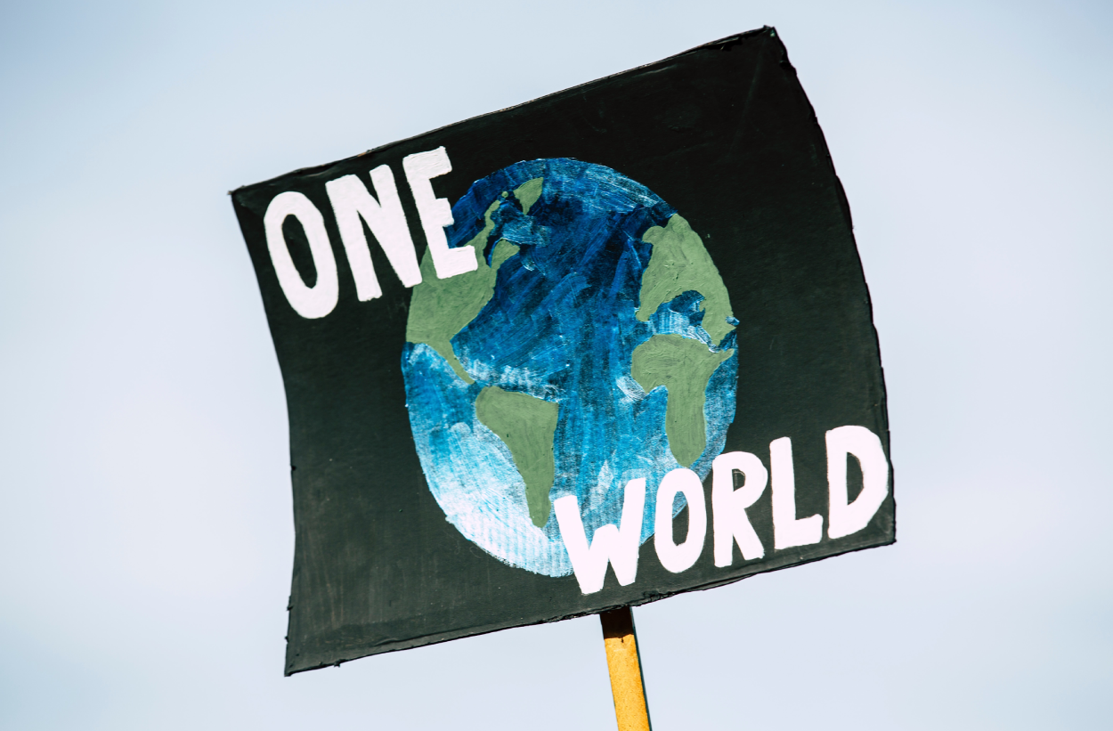 Sign with planet Earth & "One World" written on it