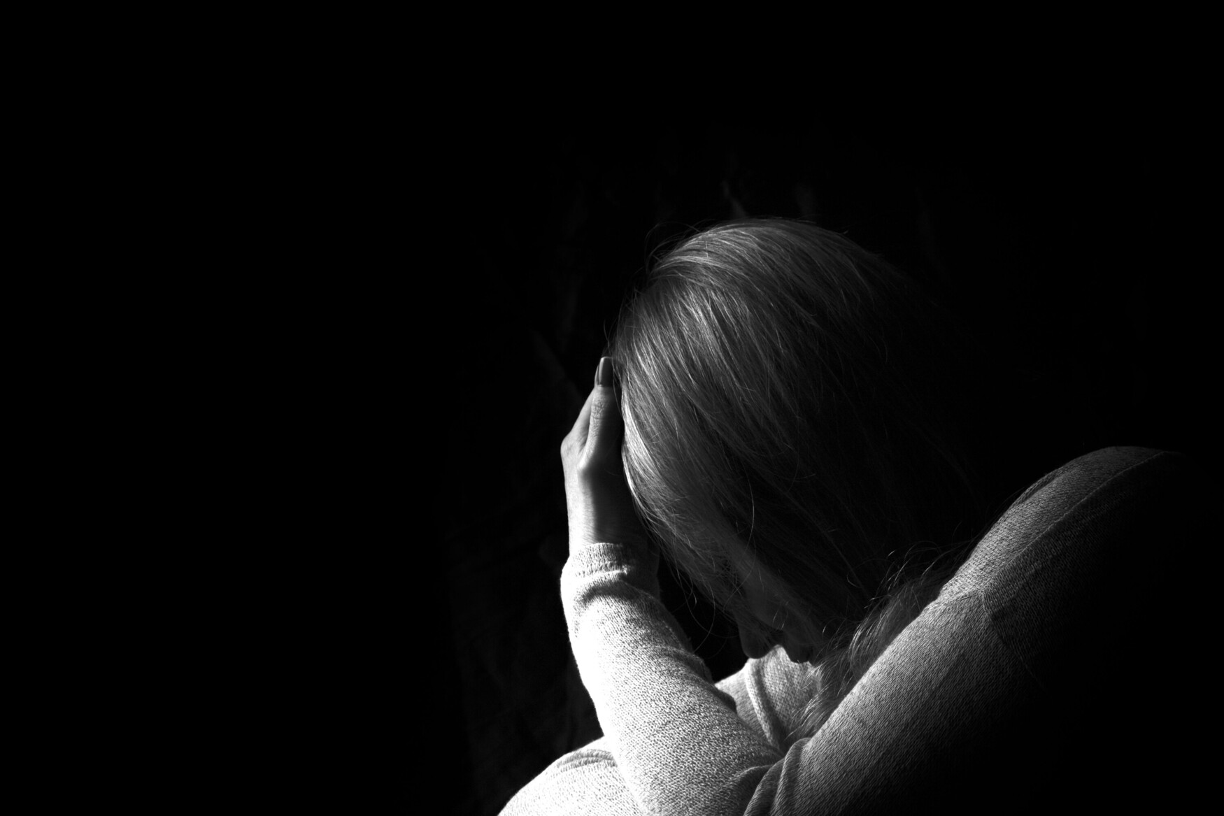 Black and white image of woman with her head in her hands