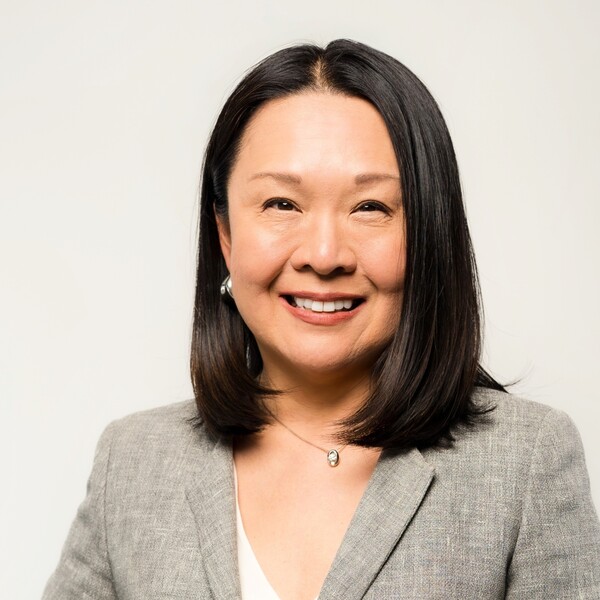 woman smiling with black hair and grey blazer
